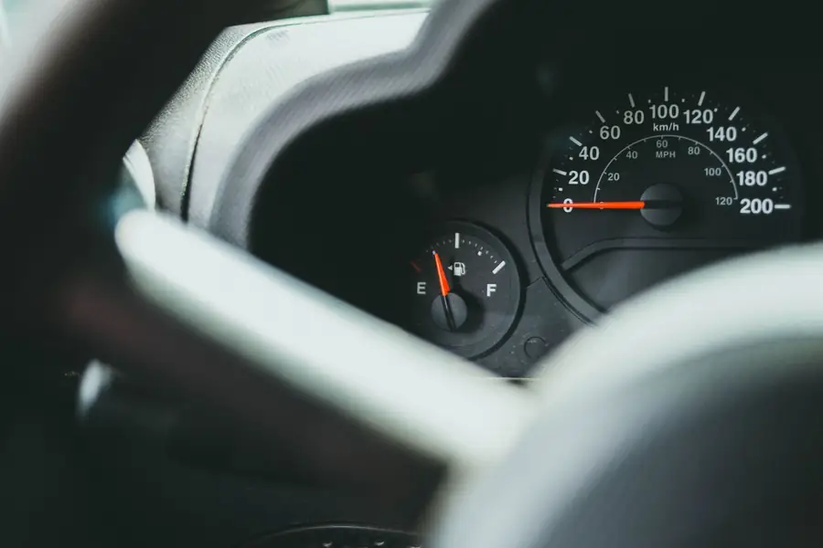 Close-up of a car dashboard with a speedometer and a fuel gauge behind the steering wheel.